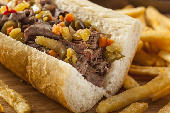 An Italian beef sandwich and french fries on a plate.
