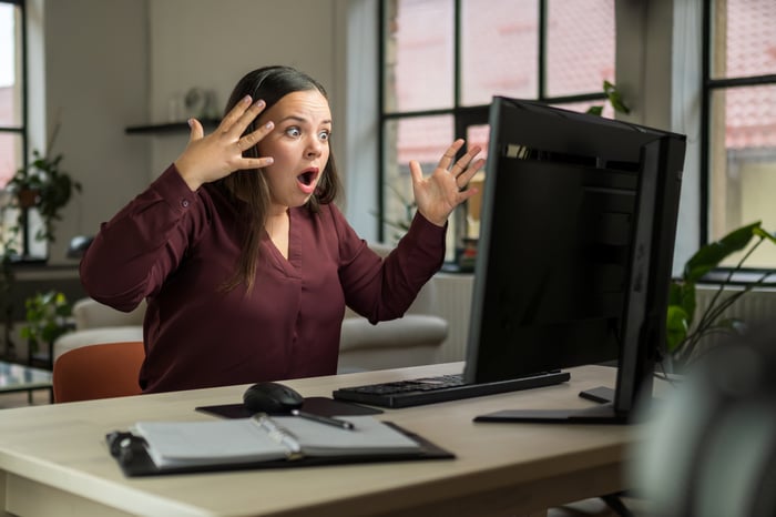 Woman looking at monitor with frustrated expression.