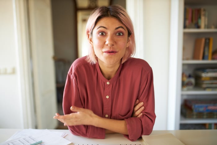 Someone seated at a table and looking surprised.