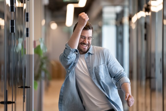 A person celebrating after receiving good news by pumping a fist in the air.
