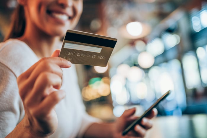 Woman holding credit card and smartphone.