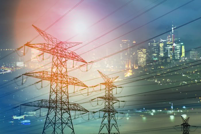 Power lines over a photo of an illuminated city. 