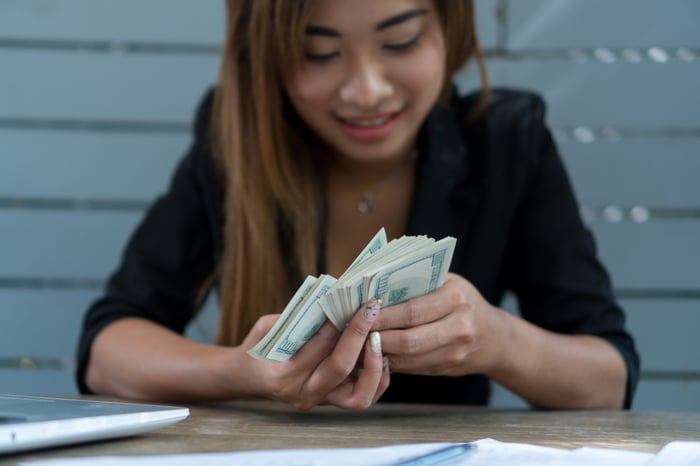 A person examining a large sheaf of $100 bills.