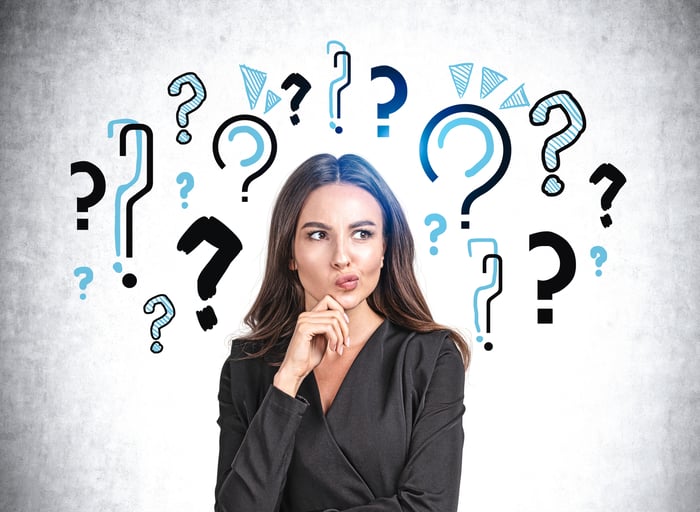 A person with a thoughtful expression with question marks superimposed in the background.