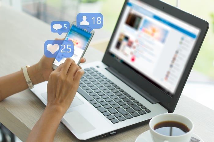 Digital heart and comment icons float above a smartphone.