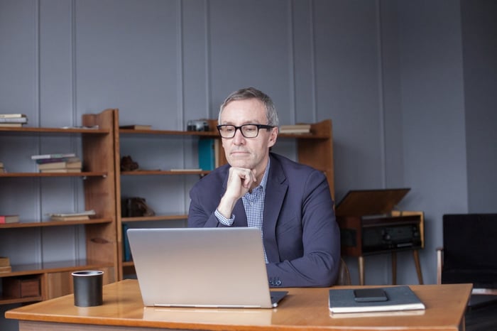 A person sits at a desk studying something on a laptop.