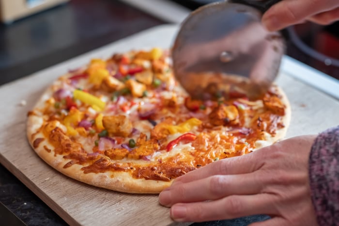 Slicing a rustic pizza with one of those handy pizza wheels.