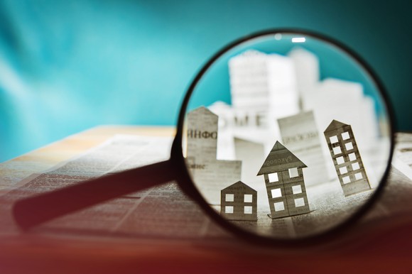 A magnifying glass looking at paper cutouts of buildings. 