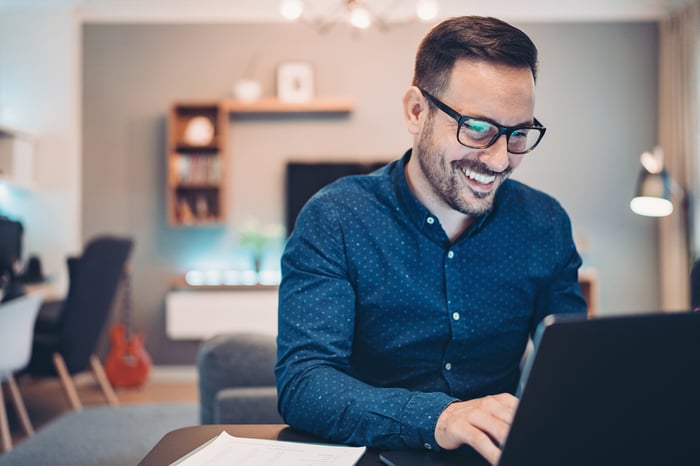 A person at a laptop smiling.