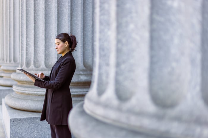 Person standing outside building with huge pillars.