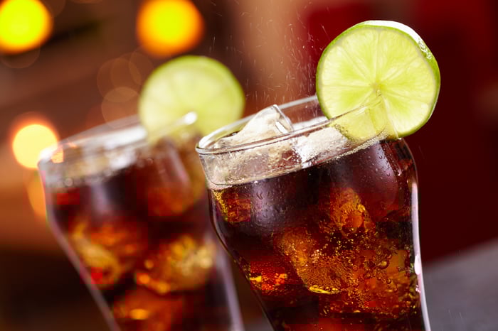 Two glasses of cola with lemon slices on the rims.