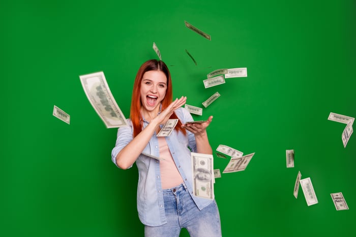 A joyous person excitedly scattering hundred-dollar bills.