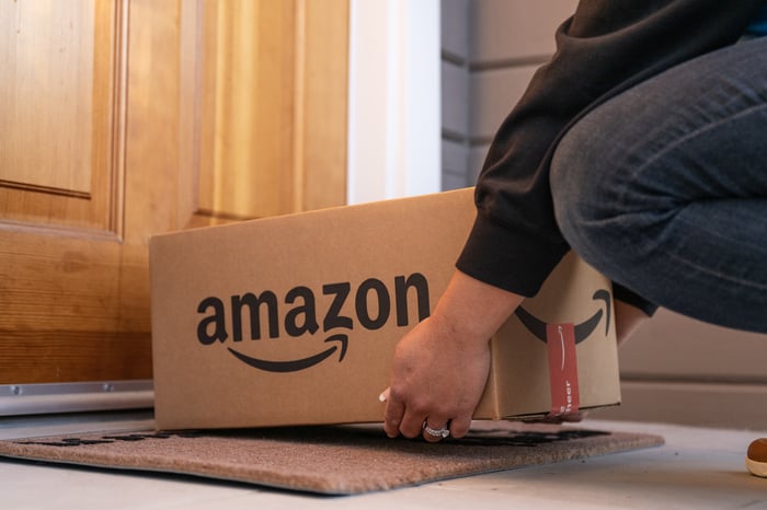 Person placing an Amazon package on a doormat.