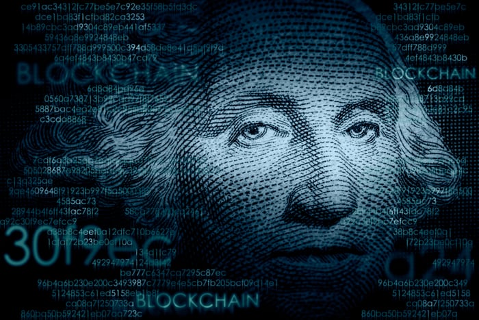 An image of George Washington on the face of the one dollar bill on top of a cloud of cryptocurrency-related terms.