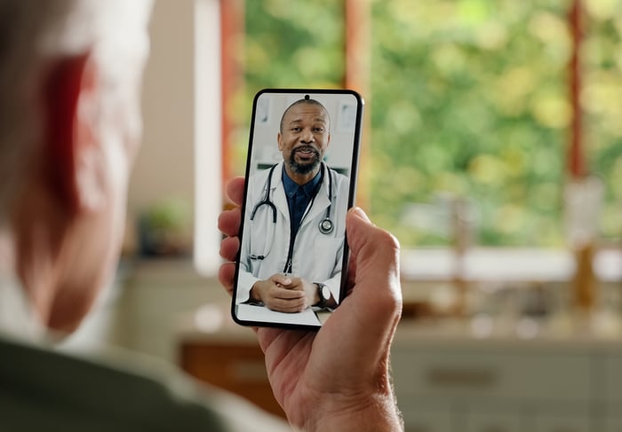 A patient holds a smartphone during a telehealth consultation.