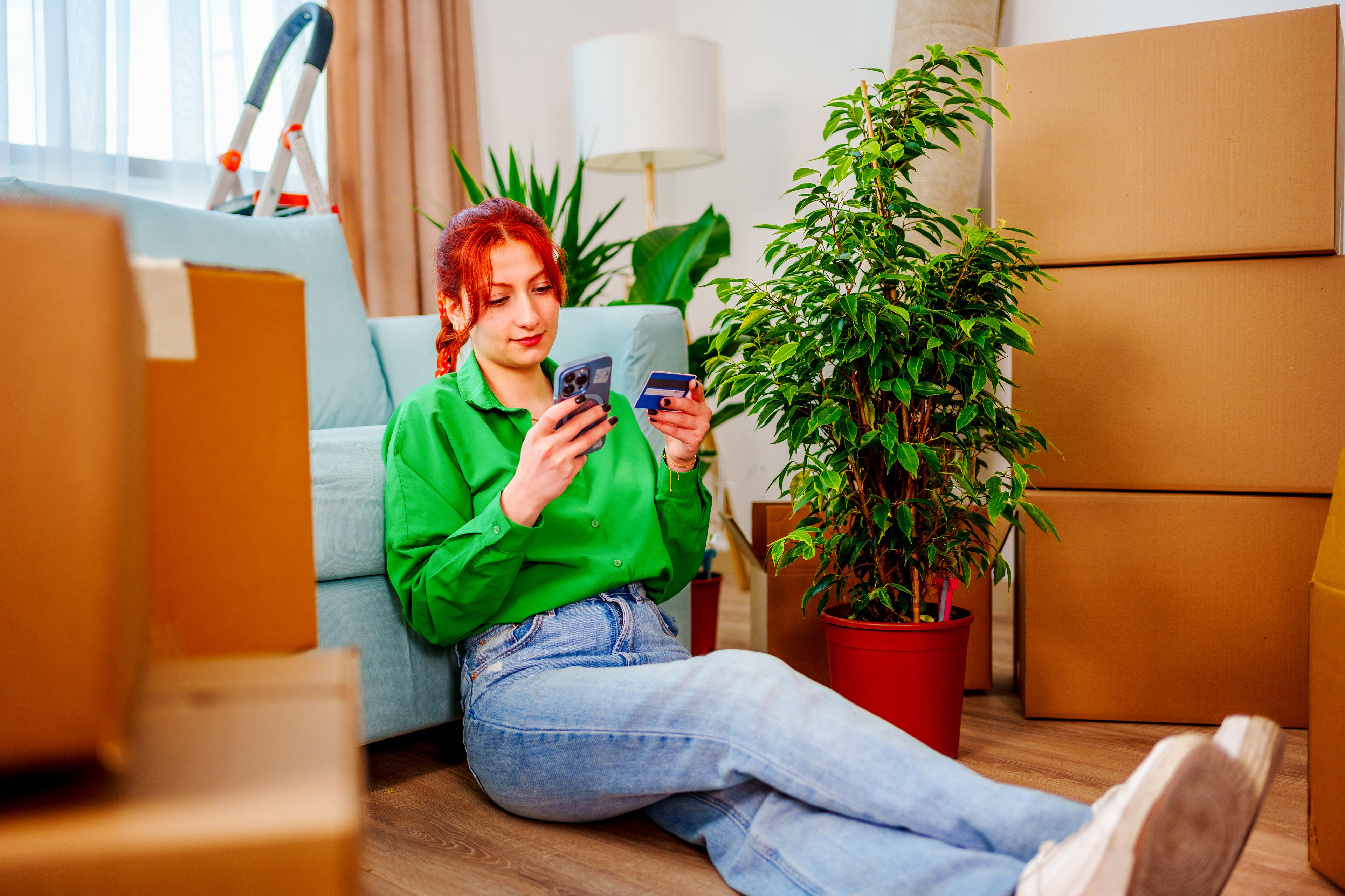 A person sitting on the floor shopping for something online on their phone. 