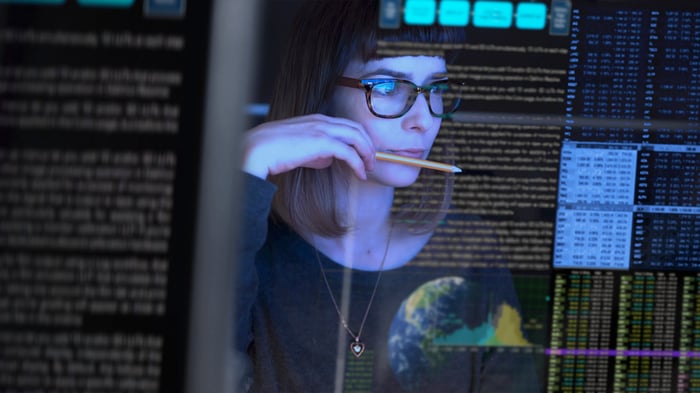 An IT professional studies a computer monitor.