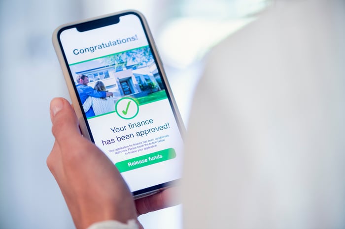 A person holding a phone with a loan approval notification.