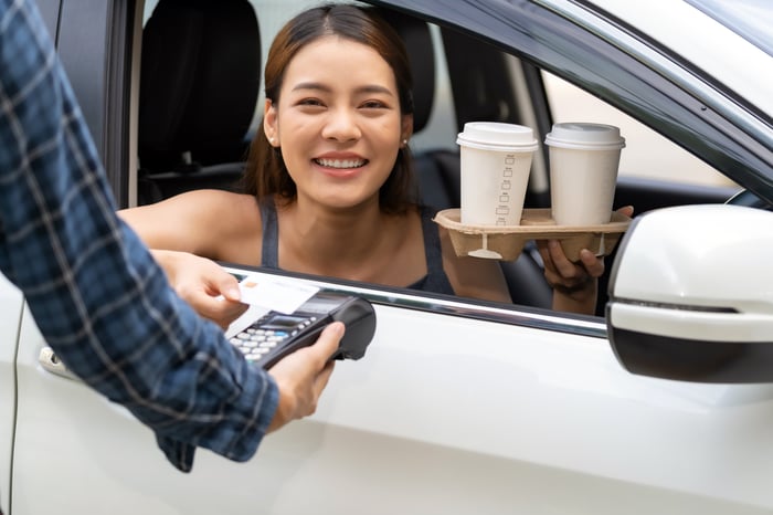Person getting coffee through a drive-thru.