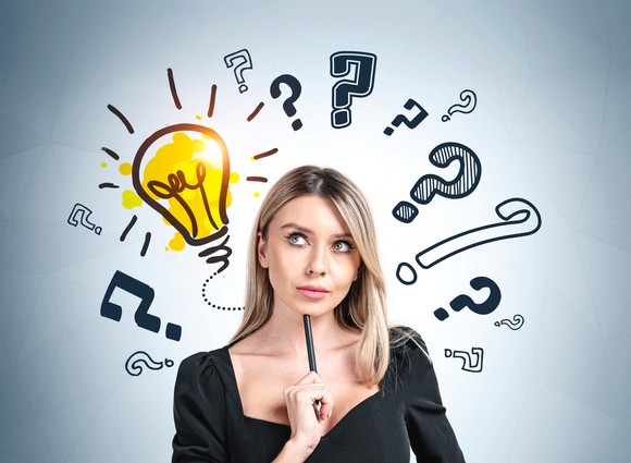 Multiple question marks and one drawing of a light bulb surrounding a person's head.