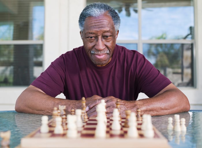 Elderly man carefully studying a chess board. 