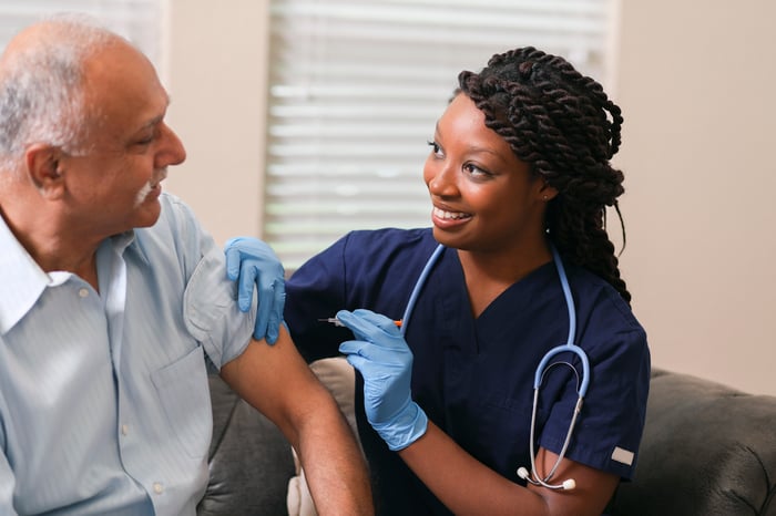 A person receiving a vaccine from a nurse.