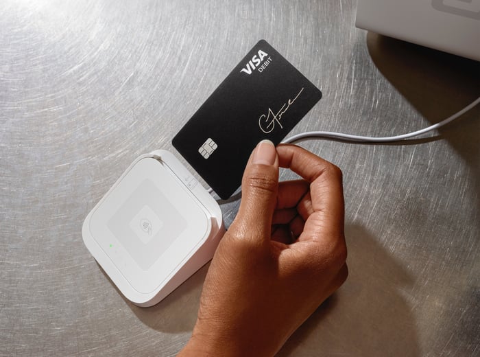 A person placing a Cash App Card into a Square ecosystem credit card point-of-sale device.