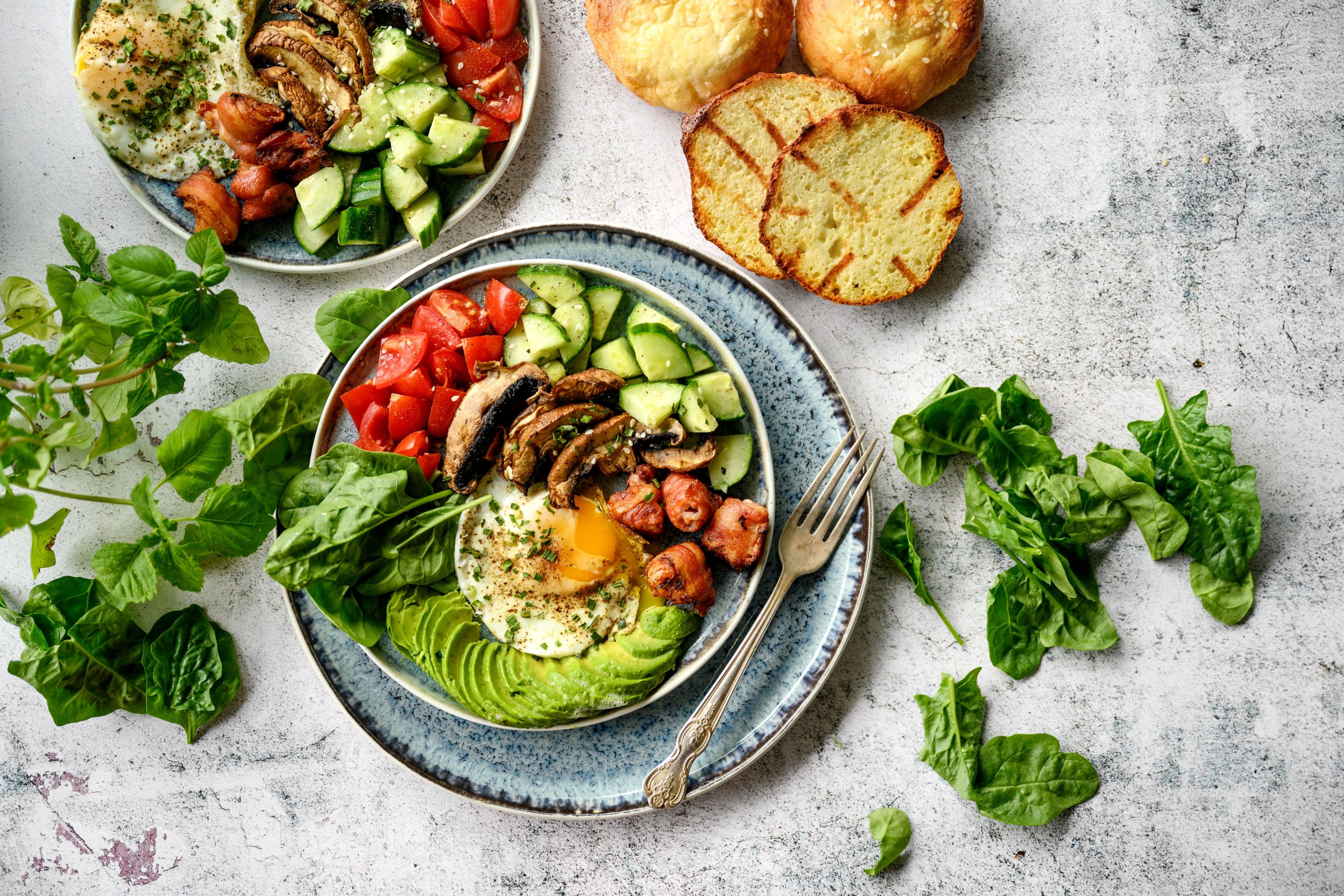 An array of brightly colored vegetables sit on two plates at a table.