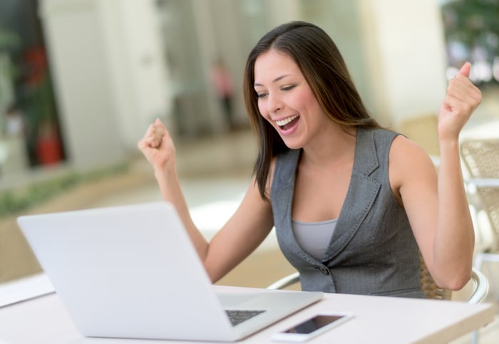 A smiling person looking at a laptop.