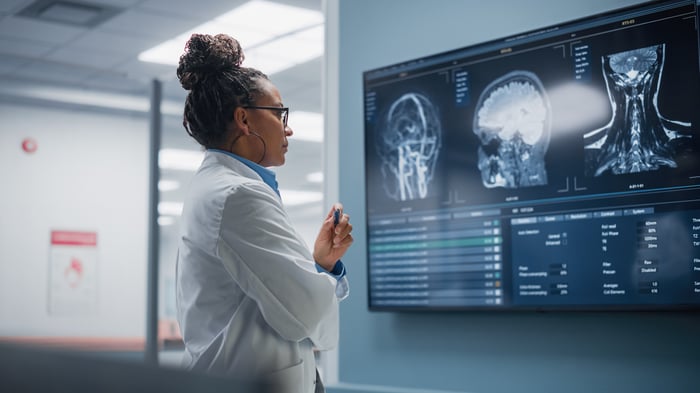 A doctor inspecting an X-rays on a wall-mounted screen.