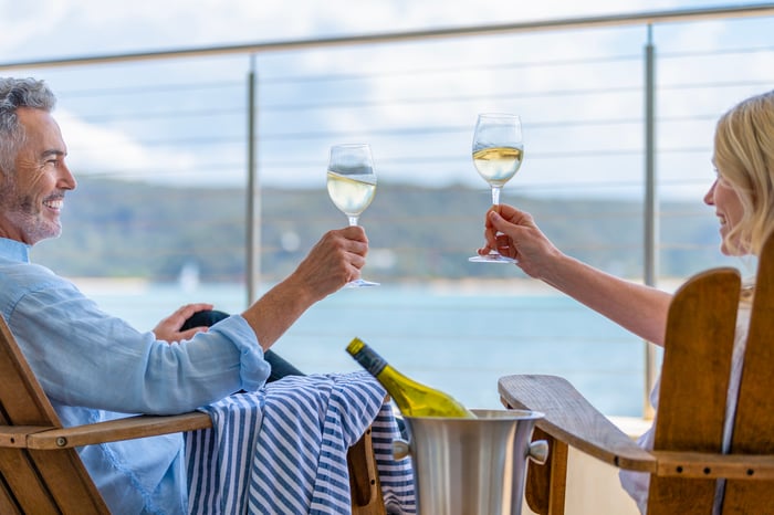 Two passengers clink glasses on the deck of a cruise ship. 