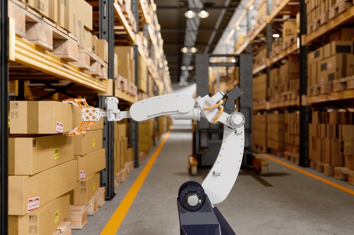 A robotic machine picking a cardboard box in a warehouse.
