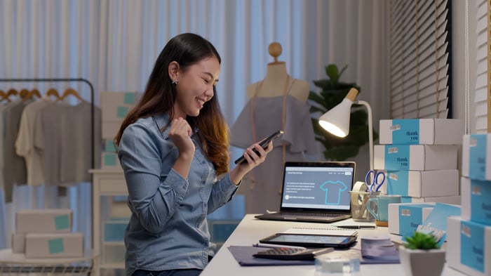 Person sitting at a desk with boxes, selling stuff online. 