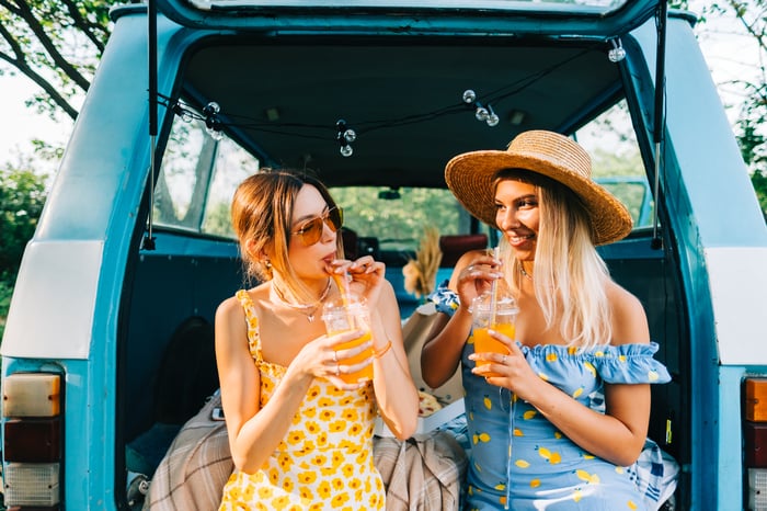 Two friends share lemonade in the back of a van.