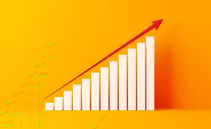 A bar chart on an orange background of increasing value with an arrow above the bars.