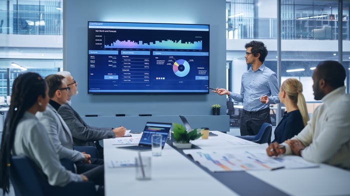 A team of people studies a chart in a meeting room.