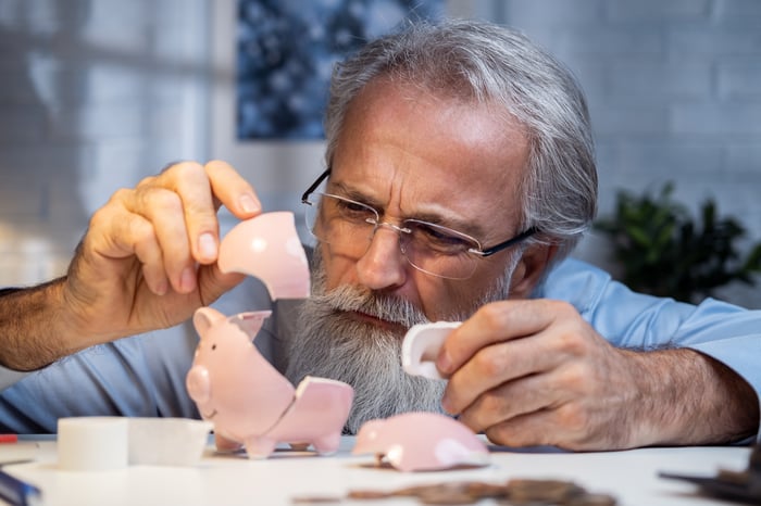 A person rebuilding a broken piggy bank, piece by piece.