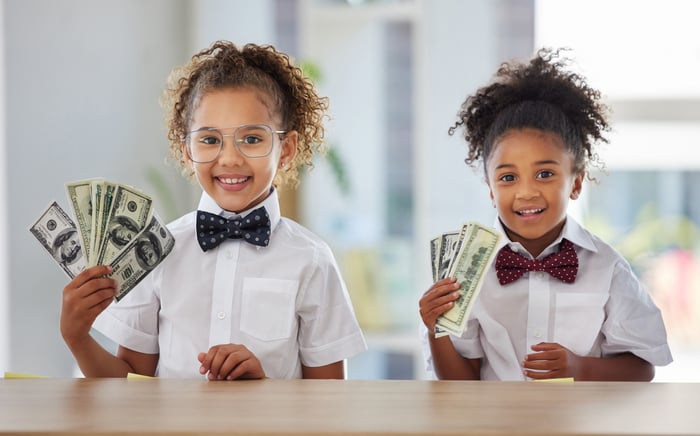 Two kids holding American currency.