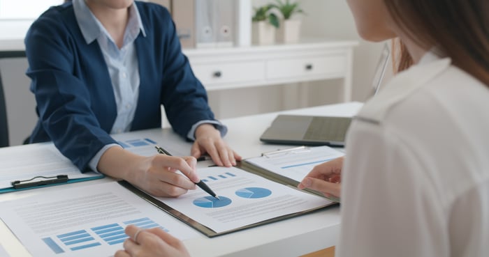 Investment advisor pointing at stock charts.