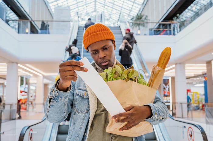 A person looks at a grocery receipt with disappointment.
