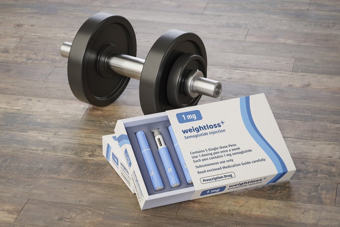 Package of weight loss drug next to a barbell.