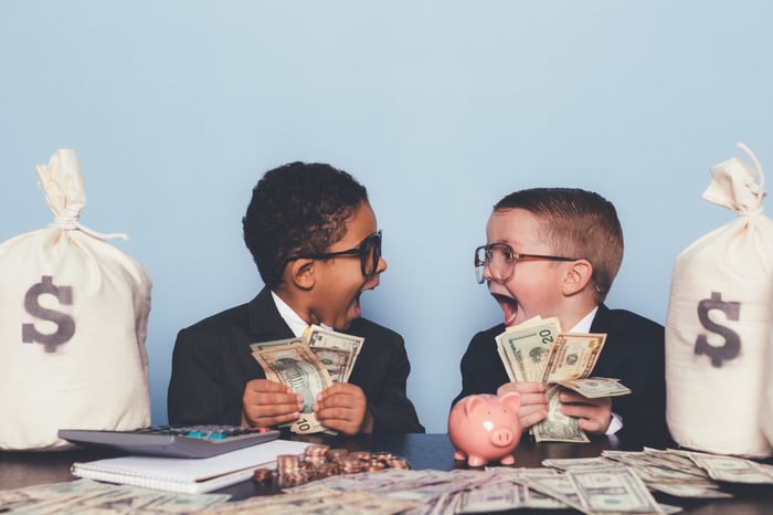 Two kids celebrating with piles of money.