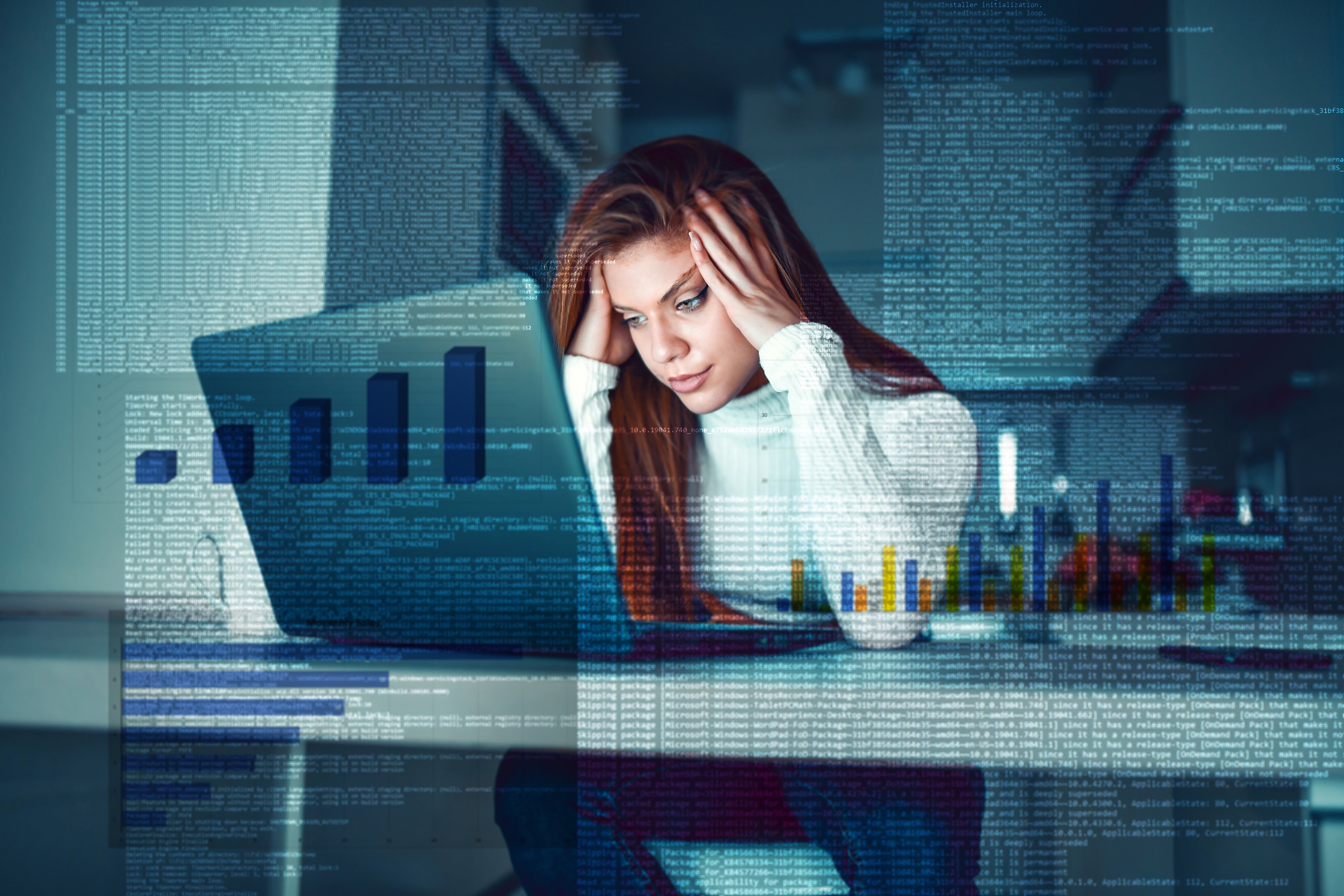 An investor touches her head in frustration while sitting at a desk in front of a laptop in an office.