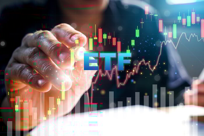 A finger pointing to a stock chart with ETF displayed in the foreground.
