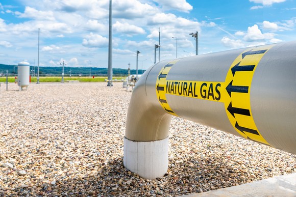 Large outdoor natural gas pipeline with yellow label and arrows indicating flow direction.