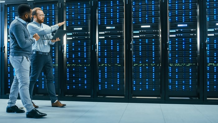 Two engineers walking by a row of servers in a data center.