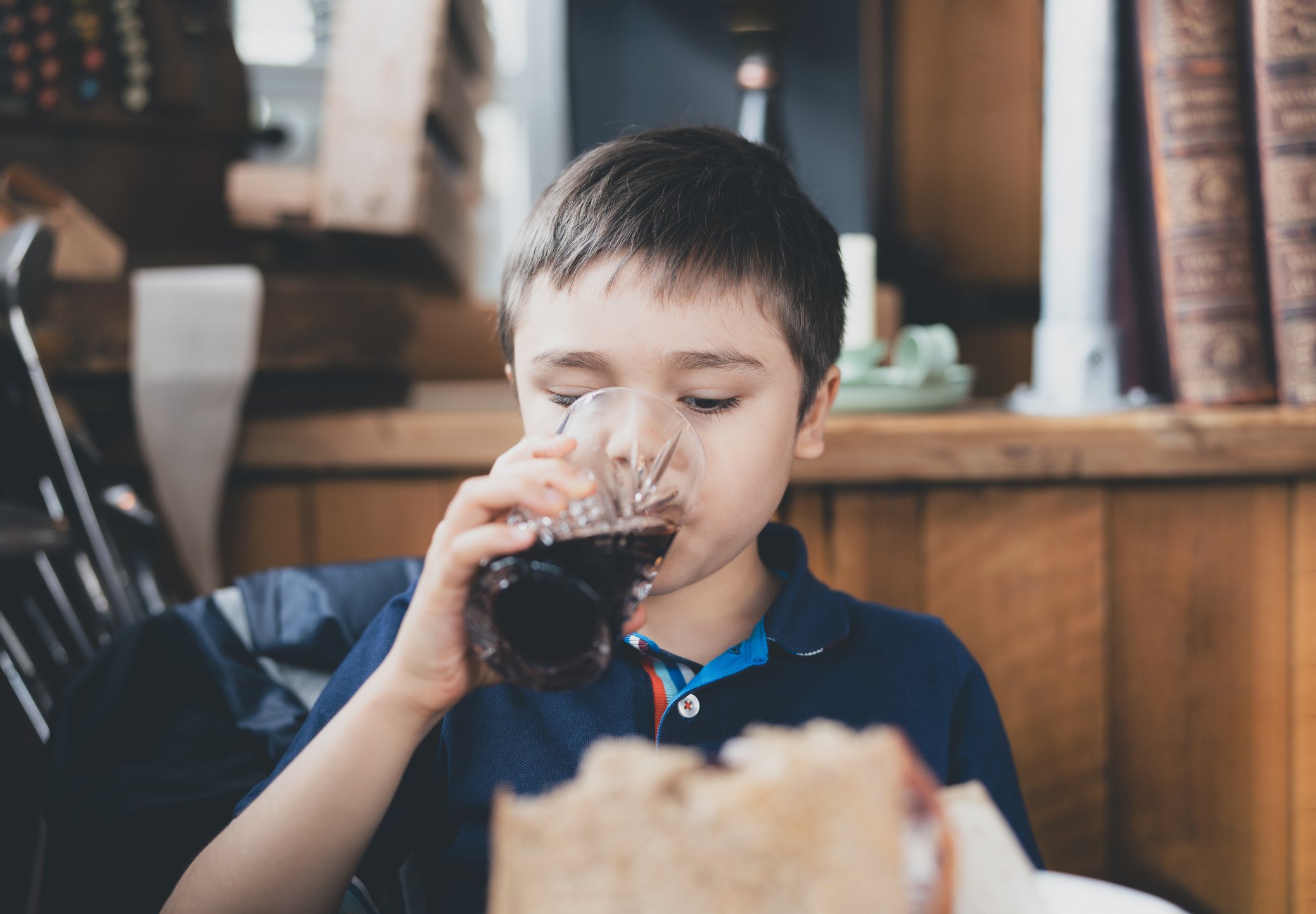Someone drinking soda out of a glass cup.