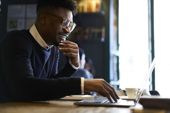 A young person smiles while working on computer.