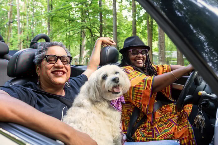 Two people and a dog for a drive in a convertible.