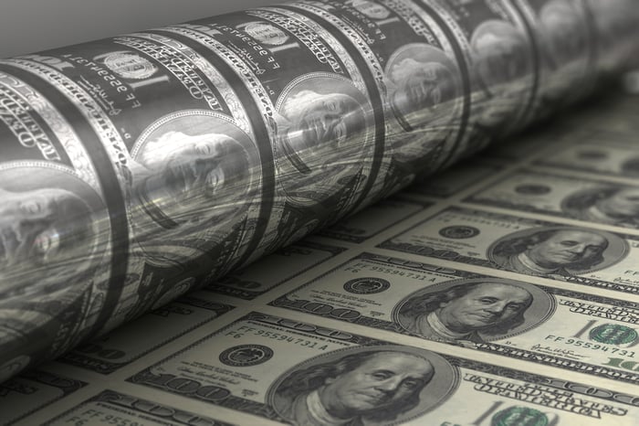 Dollar bills being printed on a machine.